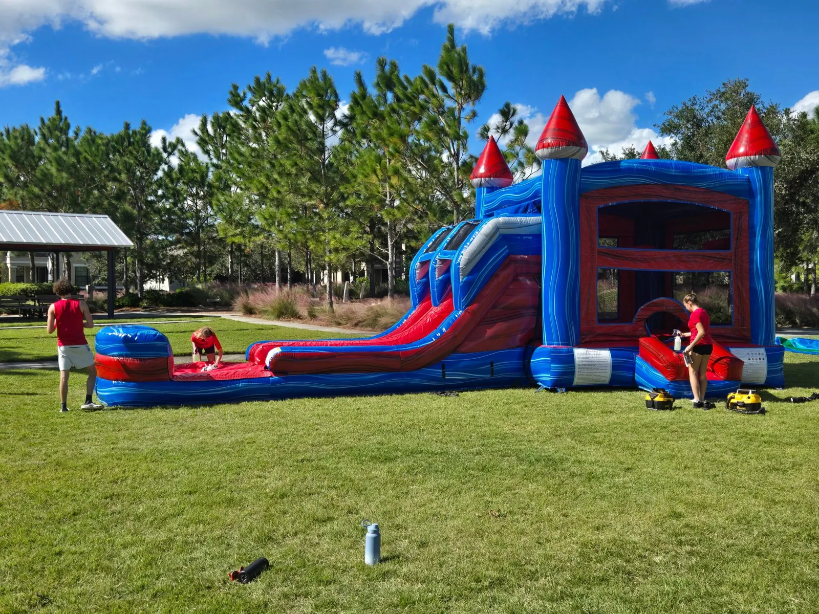 A red and blue castle bounce combo set up by SWAG on a sunny park lawn
