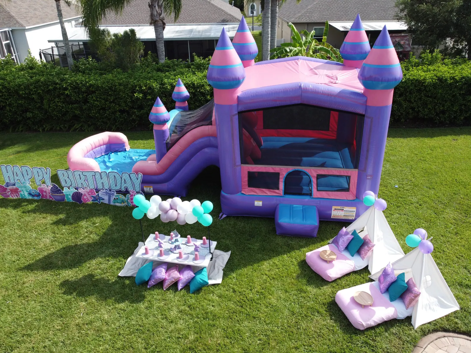 A mermaid themed backyard party with a bounce combo, picnic table and teepees