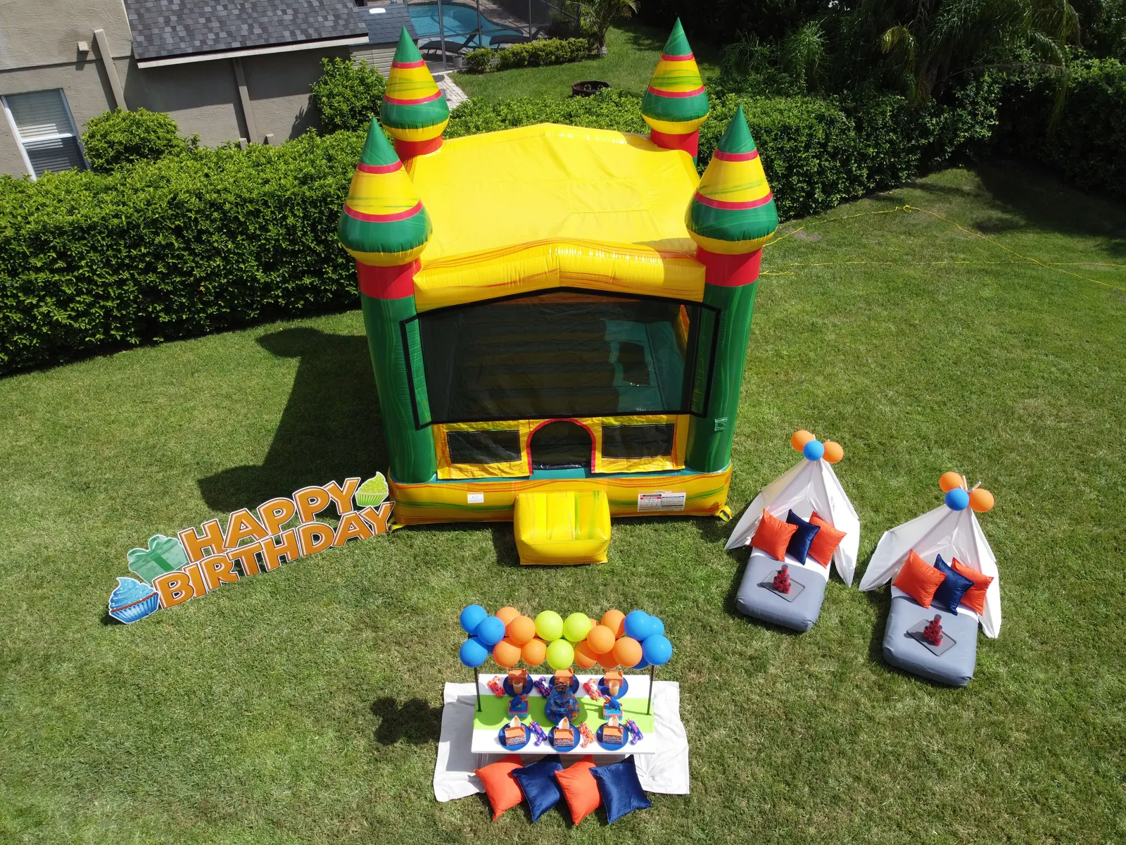 Nerf birthday party setup with a yellow castle bouncer, picnic table and teepees