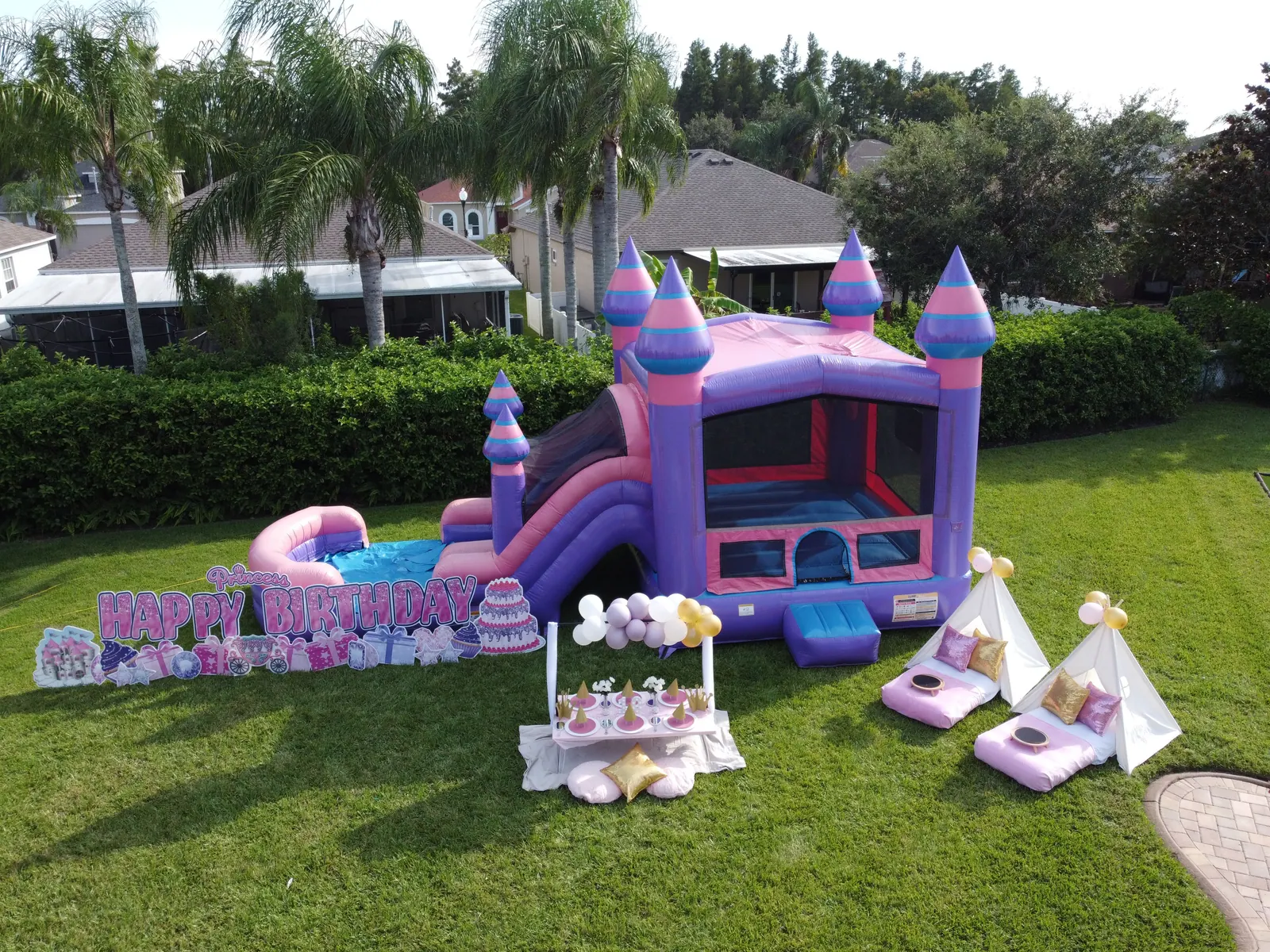 Princess birthday party setup with a castle bounce combo, picnic table and teepees