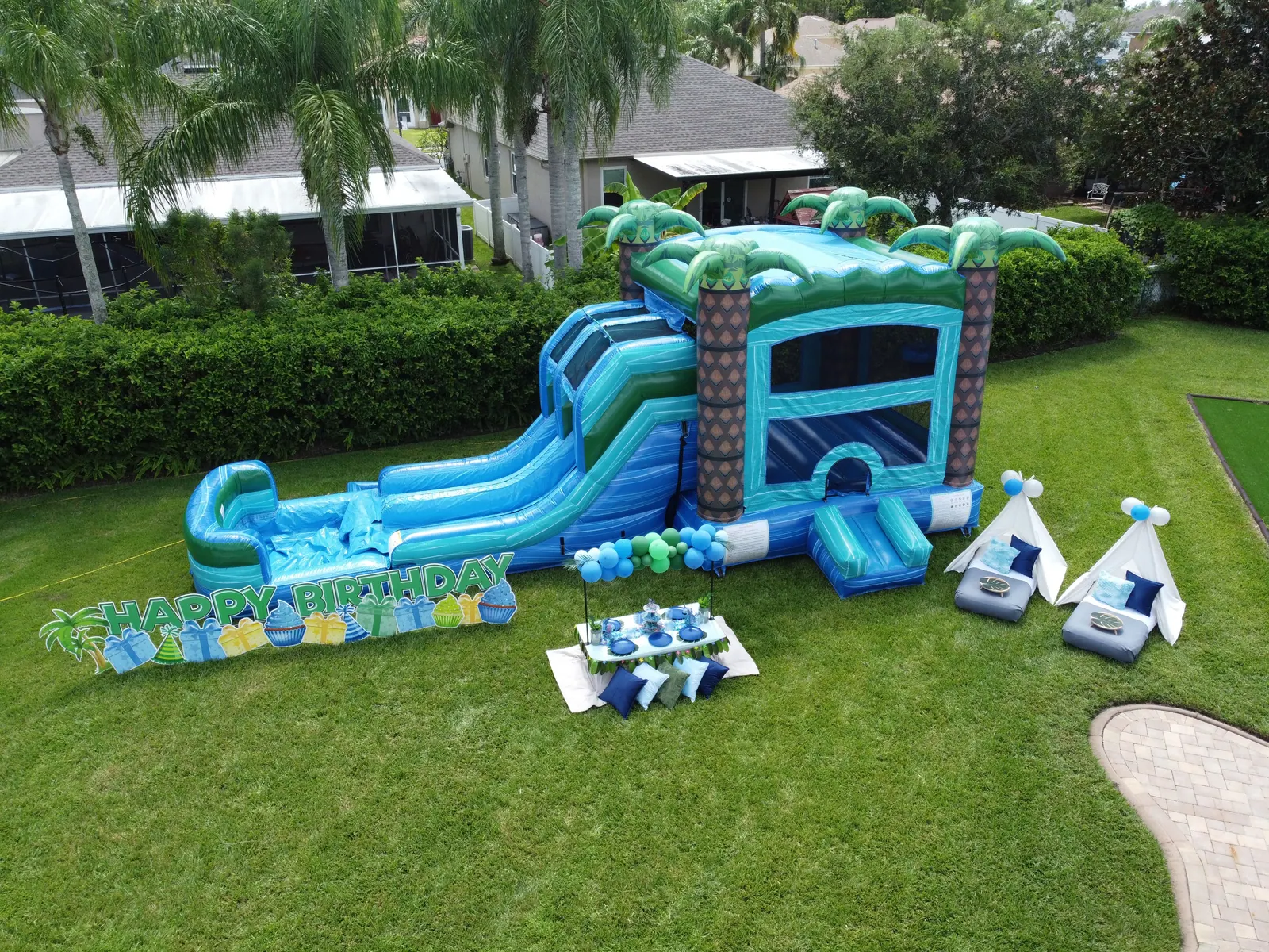 Blue Stitch birthday party setup with a tropical bounce combo and picnic table