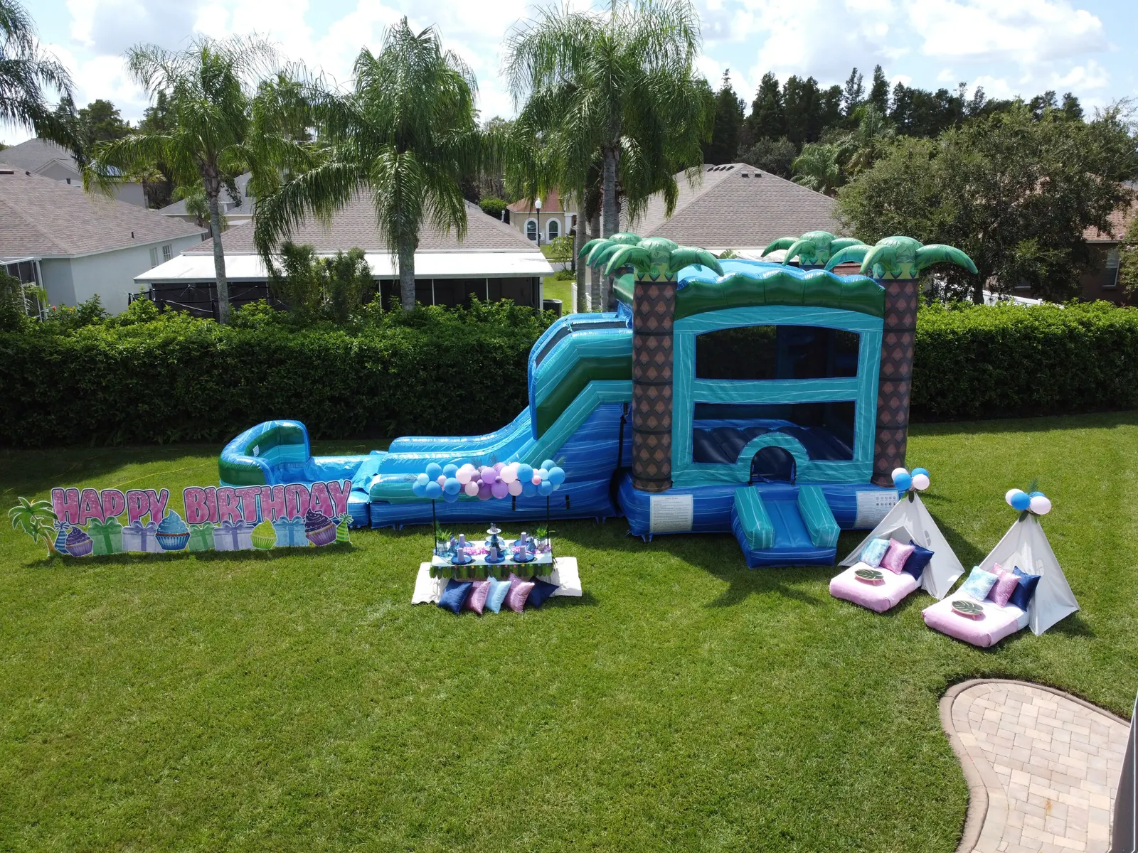 Pink Stitch birthday party setup with a tropical bounce combo, picnic table and teepees