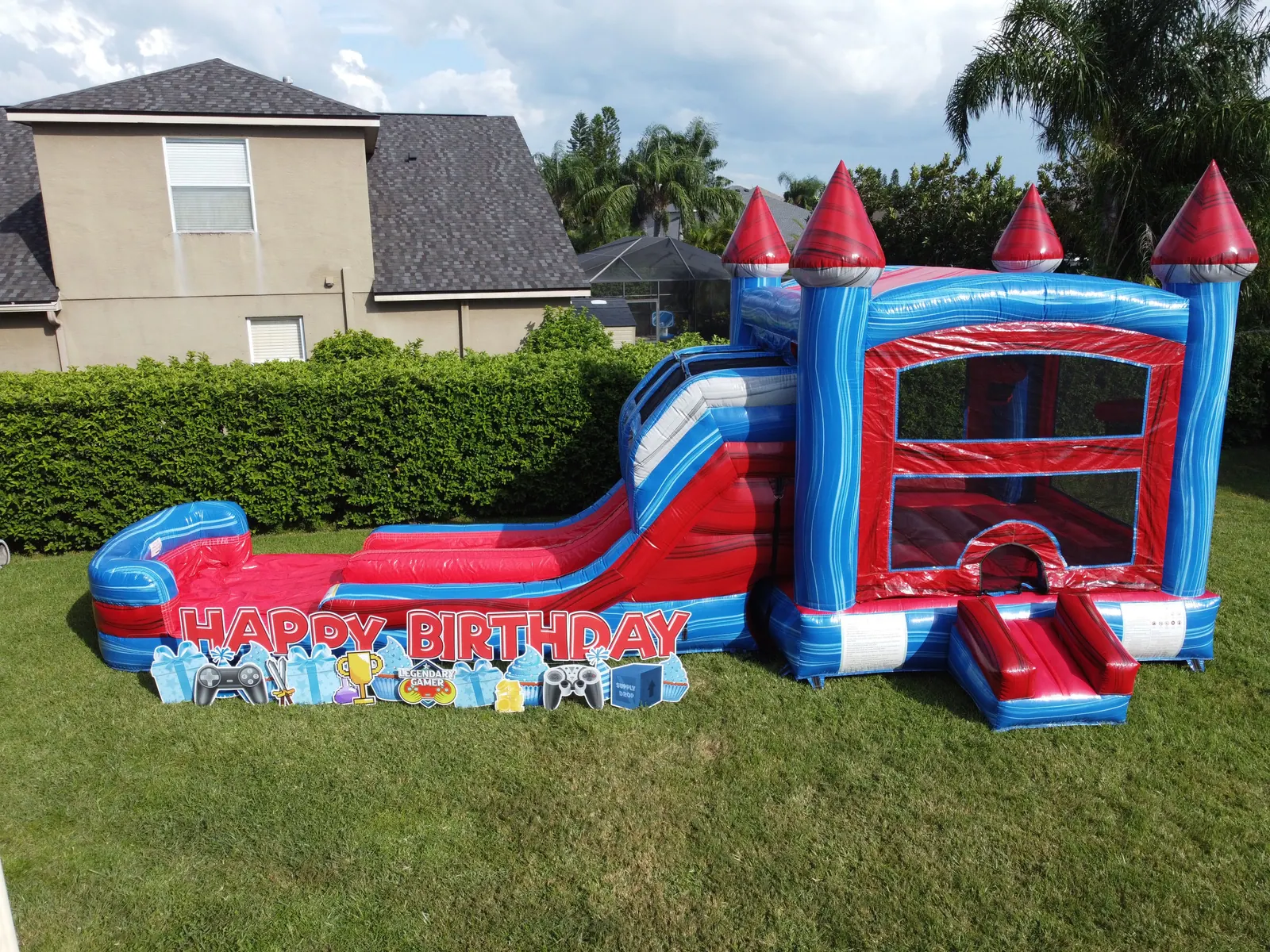 Video game birthday party setup with a red and blue castle combo and birthday yard sign